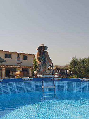a woman standing on a ladder next to a swimming pool at Casa Vacanza Villa Sole Montallegro in Siculiana