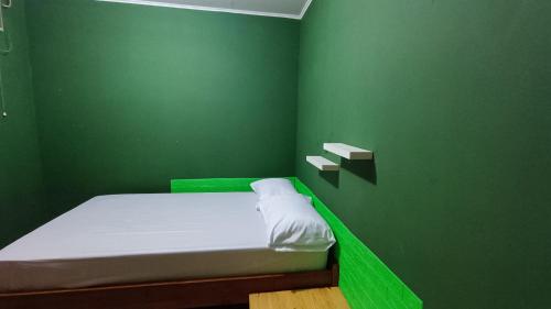 ein grünes Zimmer mit einem Bett mit einer grünen Wand in der Unterkunft OYO 91341 D'phoenix Anggrek Syariah Residence in Jakarta