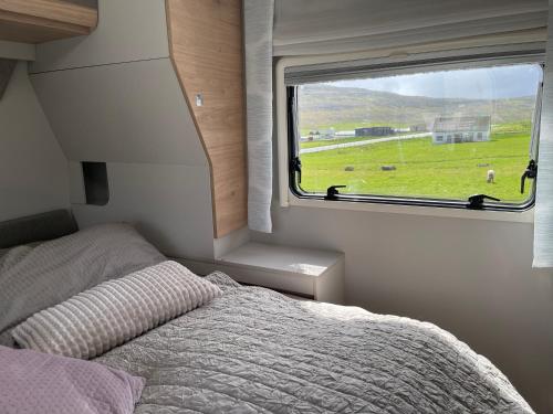 a bedroom with a bed and a window with a green field at Autocamper Tórshavn in Tórshavn