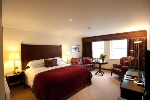a hotel room with a bed and a desk and chairs at Macdonald Norwood Hall Hotel in Aberdeen
