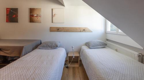 two beds in a room with a table and windows at Appartement avec RoofTop au centre de Malmedy in Malmedy