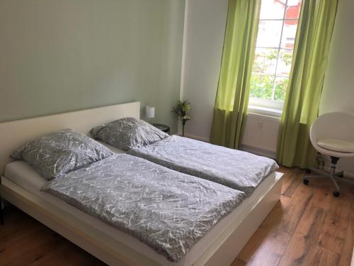 エアフルトにあるFerienwohnung Talparkの緑のカーテンと窓が備わるベッドルームのベッド1台