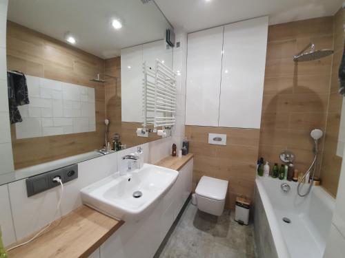 Un baño con lavabo, inodoro y bañera. en Nadmorski apartament premium, en Gdynia