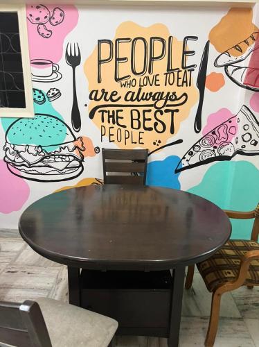 a table and chairs in front of a wall with a mural at Krazy Solo Hostel in Mumbai