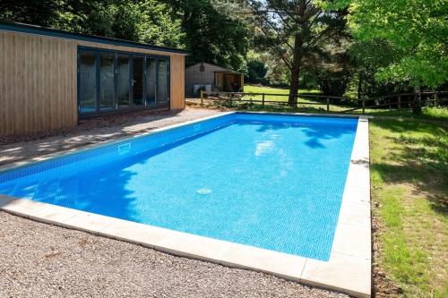 a swimming pool with blue water in a yard at Osbornes Holiday House near Exeter with swimming pool in Exeter