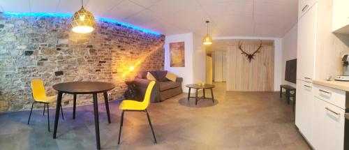 a living room with a table and chairs and a brick wall at La Librairie in Francorchamps