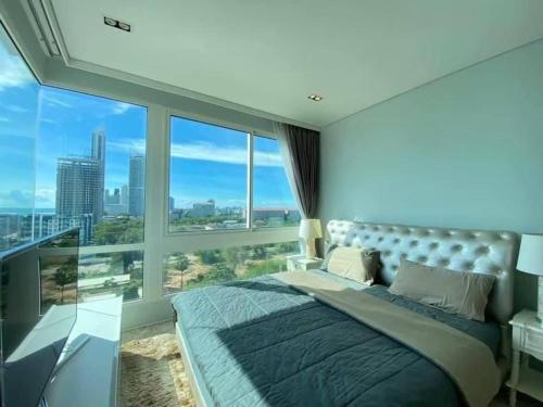 a bedroom with a large bed and a large window at Veranda Residences Pattaya By Phung in Jomtien Beach