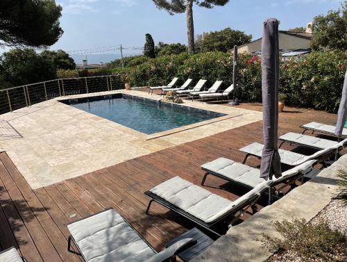 a swimming pool with lounge chairs and an umbrella at Villa Le Patio à 20 m de la mer in Saint-Peïre-sur-Mer