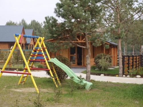 un parque infantil frente a una casa con tobogán en Radawa Leśne Domki - Leśny domek, en Radawa