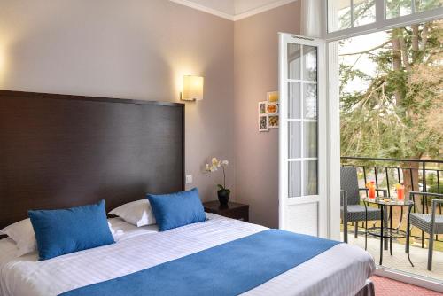 1 dormitorio con 1 cama con almohadas azules y balcón en Logis Hôtel Restaurant Le Parc en Salbris
