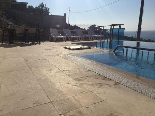 a swimming pool with chairs sitting next to the water at Dilbar Villa in Akbük