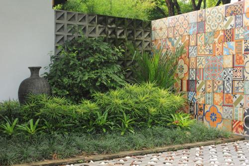 Komoreya Guesthouse في Kejayan: حديقة بحائط فسيفساء ومزهرية ونباتات