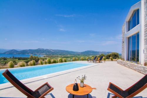 eine Villa mit einem Pool mit einem Tisch und Stühlen in der Unterkunft Villas Mandalos in Palairos