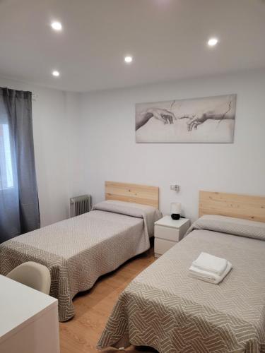 a bedroom with two beds and a painting on the wall at BRiSaS DeL NoRTe in Gijón