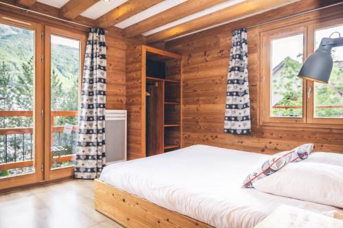 a bedroom in a log cabin with a bed and windows at Chalet Melezor in Saint-Chaffrey