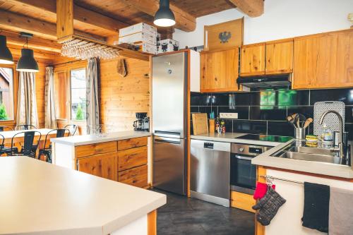 cocina con armarios de madera y nevera de acero inoxidable en Chalet Melezor, en Saint-Chaffrey