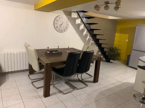 a dining room table with chairs and a clock on the wall at Rocroi: Gîte de Bourgogne in Rocroi