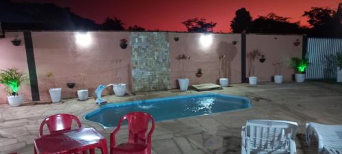 eine Terrasse mit Pool, Stühlen und einem Tisch in der Unterkunft Chalés Recanto dos Pássaros in São Thomé das Letras