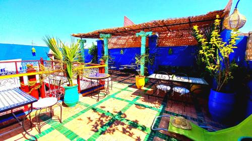 a deck with chairs and tables and a blue building at Riad R&ecirc;ve d Antan in Marrakech