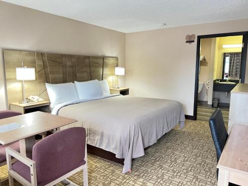 a hotel room with a bed and a table and chairs at Viking Arms Inn - Ludington in Ludington