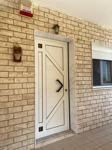 a white door on the side of a brick building at Wine & Olive Studio in Gerakini