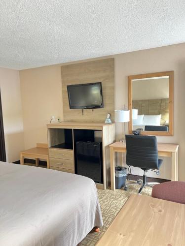a hotel room with a bed and a desk with a television at Viking Arms Inn - Ludington in Ludington