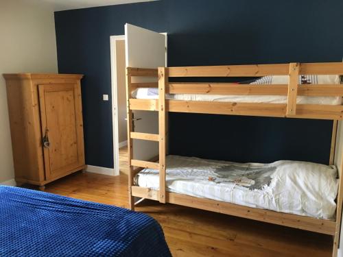 1 dormitorio con 2 literas y pared azul en Le Gîte des Murmures, en Urcel