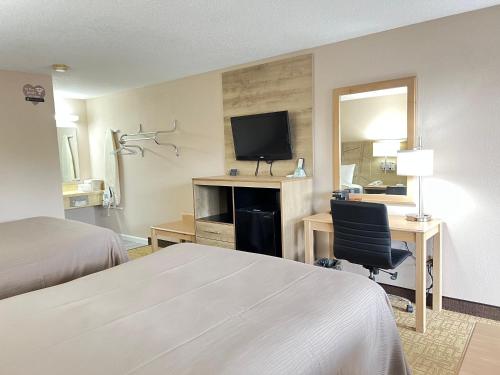 a hotel room with a bed and a desk with a television at Viking Arms Inn - Ludington in Ludington