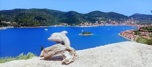 a statue of a squirrel sitting on a rock overlooking a lake at Odysseion Apartments in Vathi, Ithaka