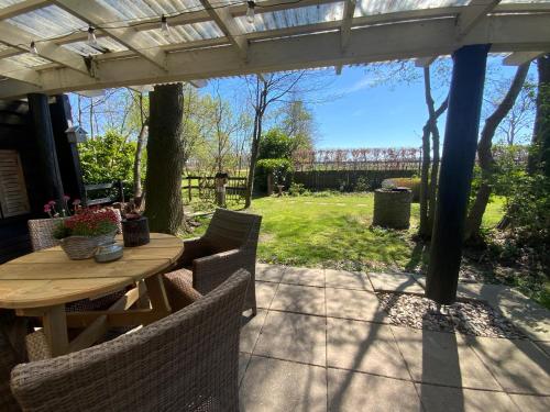 a wooden table and chairs under a pergola at B&B de Tuinfluiter in Nieuwleusen