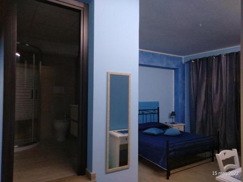 Dormitorio azul con cama y espejo en ALLOGGIO BLU nel CUORE DI SORIANO, en Soriano nel Cimino