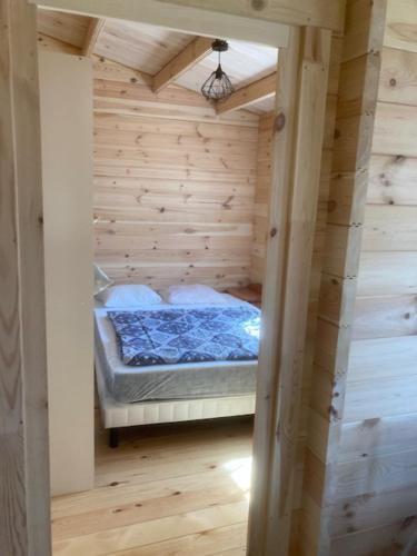 Habitación pequeña con cama en una pared de madera. en Les Pins en Excenevex