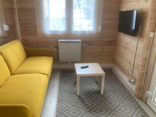 a living room with a yellow couch and a table at Les Pins in Excénevex