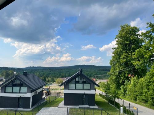 duas casas numa estrada com árvores ao fundo em Domy na Roztoczu Aleja Lipowa A H em Zwierzyniec