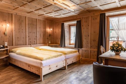 a bedroom with two beds and wooden walls at Hotel Landgasthof Staila in Fuldera