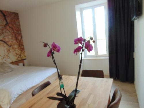 a vase with purple flowers on a table in a bedroom at Relais de la Diligence in La Roche-en-Brenil