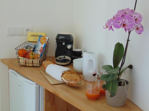 a counter top with bread and fruit and a flower at Relais de la Diligence in La Roche-en-Brenil