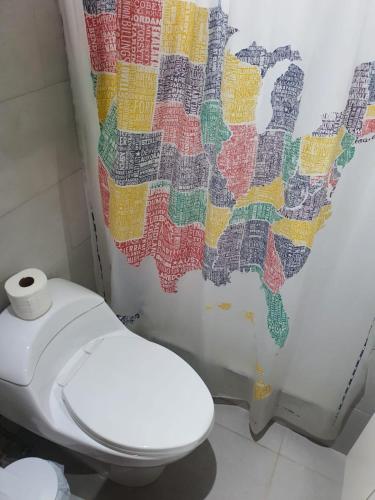a toilet in a bathroom with a map shower curtain at Sea breeze vacation ll en Condominio Verde Mar in San Juan
