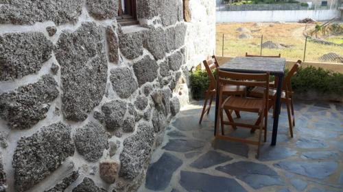 a table and chairs sitting next to a stone wall at Casa da Carreira in Amarante