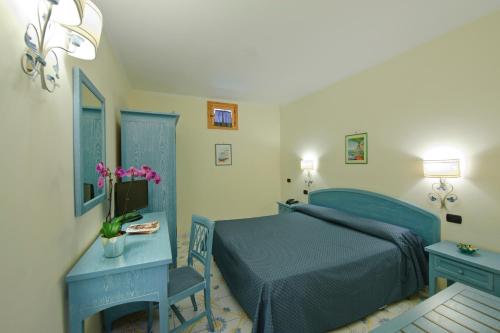 アマルフィにあるホテル ラ ペルゴラのベッドルーム1室(青いベッド1台、テーブル、デスク付)