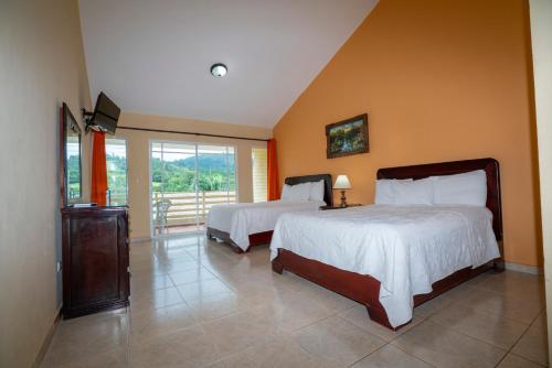 a bedroom with two beds and a balcony at Jarabacoa River Club & Resort in Jarabacoa