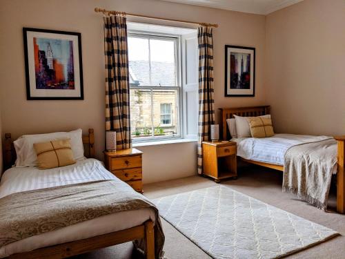 a bedroom with two beds and a window at Huge 4 Bed Apt - Perfect Base to Explore The Borders in Jedburgh