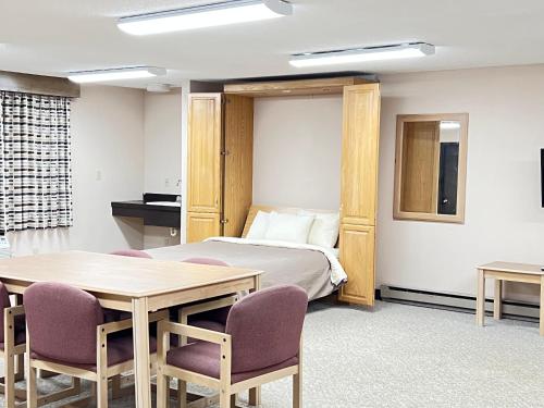 a room with a bed and a table and chairs at Viking Arms Inn - Ludington in Ludington