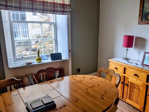 uma mesa de madeira e cadeiras num quarto com uma janela em Huge 4 Bed Apt - Perfect Base to Explore The Borders em Jedburgh