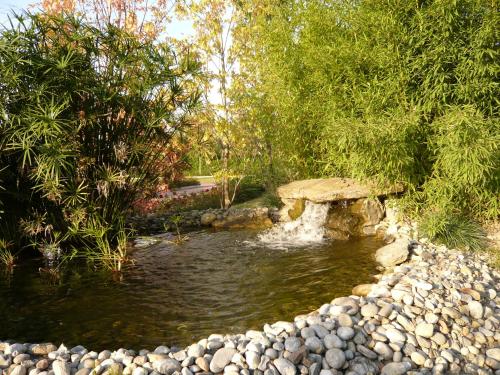 a pond with a stone bridge in a garden at Monica Hotel Fiera in Pregnana Milanese