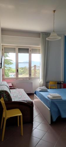 a bedroom with two beds and a chair and windows at b&b L`Oasi in Casal Velino