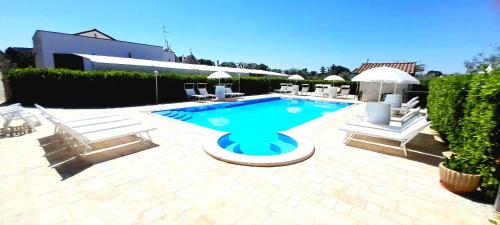 - une piscine avec des chaises longues blanches dans l'établissement Trulli Nuova Aia Resort, à Alberobello