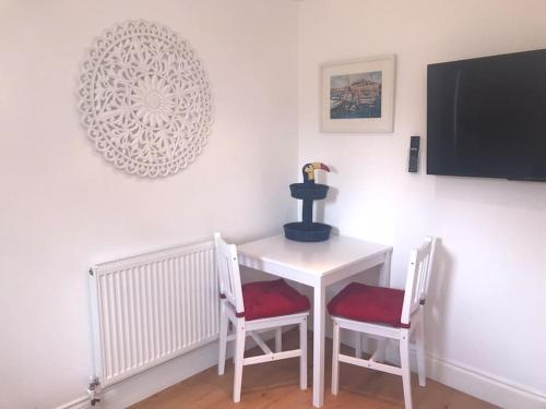 a white table with two chairs and a table with a vase at Woodside Annexe in Paignton