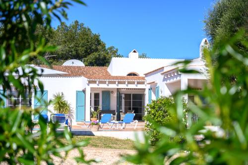 a white house with blue chairs in the yard at Quite villa with private pool in Binibeca in Binibeca