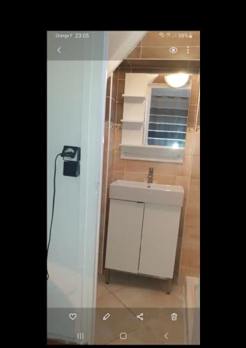 une salle de bain avec un lavabo blanc et un miroir dans l'établissement Appartement chaleureux à 35mn de Paris, à Corbeil-Essonnes